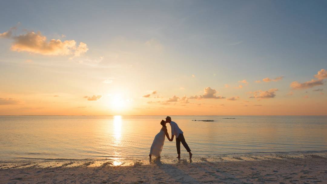 man and woman standing on shore kissing