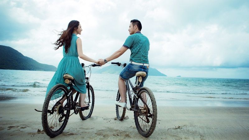 couple riding bicycles on a beach